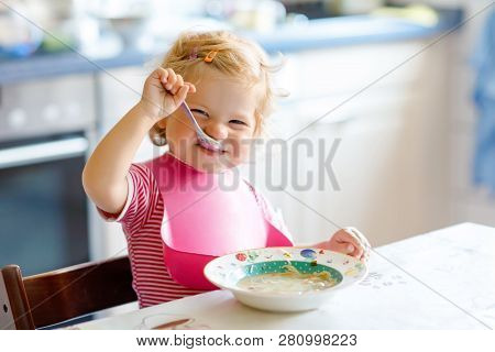 Adorable Baby Girl Eating From Spoon Vegetable Noodle Soup. Food, Child, Feeding And Development Con