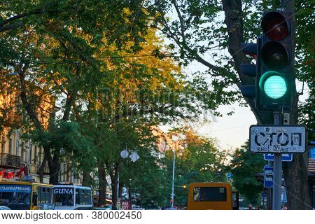 Odessa, Ukraine - August 4, 2020: Preobrazhenskaya street near the Cathedral square and city Park, green trees and people, road with car traffic