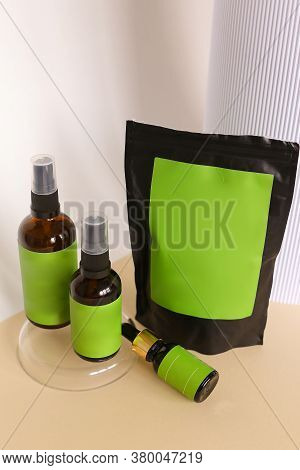 Close Up Black Doy Pack And Three Spray Bottles With Cosmetic Product, Green Space For Brand.