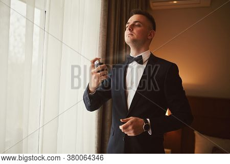 Morning Of The Groom Before The Wedding. Groom Morning Preparation. Young And Handsome Groom Sprayin