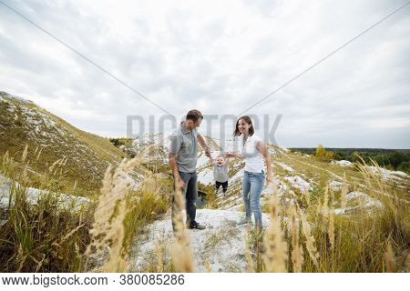 Mom, Dad Hugging Son In The Sand Mountains Enjoy And Look At Nature. Young Family Spending Time Toge