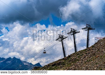 Cableway On Mountaintop In Cloudy Weather. Modern Ropeway With Benches In Amazing Mountainous Terrai