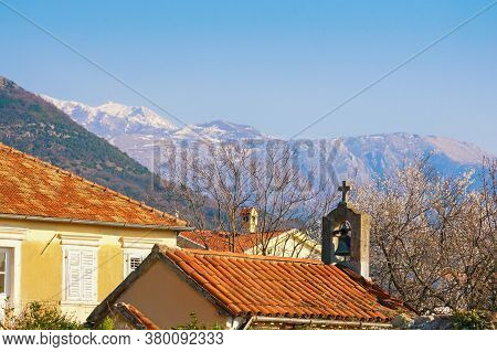 Spring In Mediterranean Village. Cherry Blossoms, Red Tiled Roofs And Small Ancient Church Against S