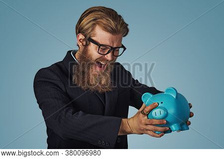 Unhappy Man In Glasses Angry At His Piggy Bank Trying To Broke It Up, Bearded Hipster Businessman Is