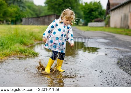 Little Toddler Girl Wearing Yellow Rain Boots, Running And Walking During Sleet On Rainy Cloudy Day.