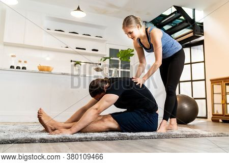 White caucasian man learning yoga at home. Female instructor or trainer coaching and adjust correct pose to student. Workout healthy lifestyle and Yoga health delivery concept.