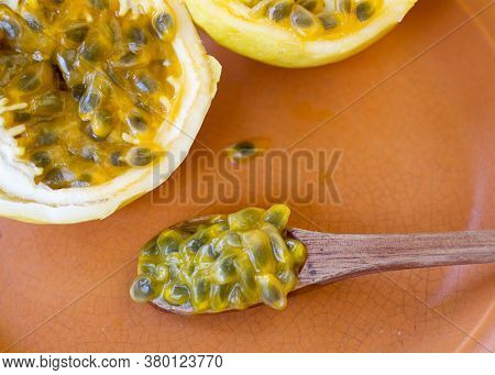 Passion Fruit Cut In Half, Ready To Be Eaten With Wooden Spoon, On Brown Plate
