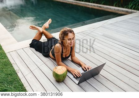Woman Freelance Work Typing On Laptop Poolside Outdoors With Fresh Coconut . Traveling With A Comput