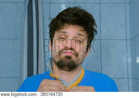 Drunken Sleepy Man With Hangover Fastening T-shirt Wrong In Bathroom Looking At Cameraas At Mirror. 