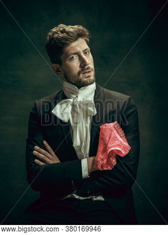 Passioned. Young Man In Suit As Dorian Gray Isolated On Dark Green Background. Retro Style, Comparis