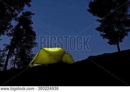 The Tent Glows In The Night. Camping By The Lake In A Pine Forest. Romantic Trip.