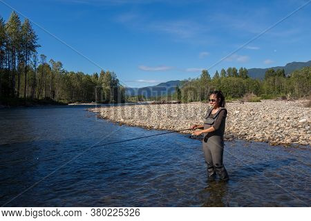 An Asian Women In Waders, Enjoying Fishing The Kitimat River, Skeena Region, In British Columbia, Ca