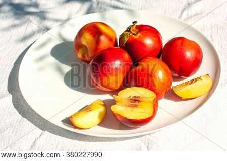 Red Ripe Organic Nectarine Fruits On The White Plate On The Table. Summertime Healthy Eating Concept