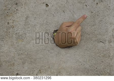 The Hand That Went Through The Concrete Wall Points To The Corner Of The Wall With A Finger.
