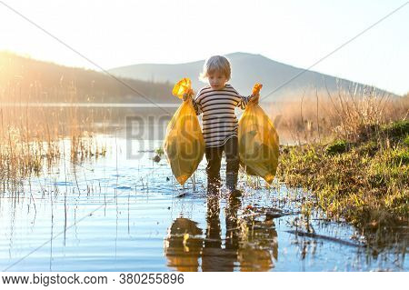 Small Child Collecting Rubbish Outdoors In Nature, Plogging Concept.
