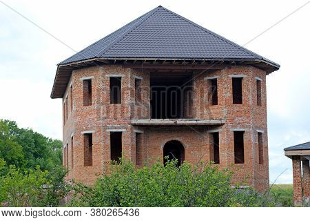 Facade Of An Unfinished Twostory House With No Red Brick Windows. Large House With Rounded Corners A
