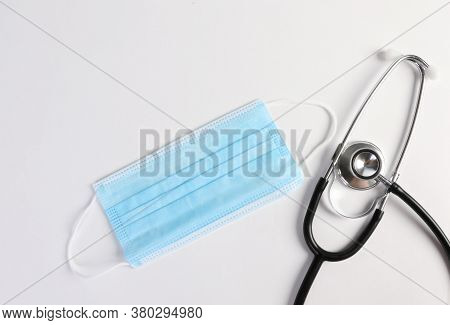 Blue Face Mask, Stethoscope On White Background. Face Mask Is Equipment For Prevent Virus Or Air Pol