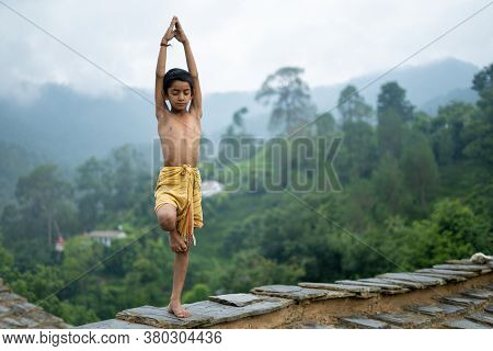 A Young Indian Cute Kid Doing Yoga In The Mountains,wearing A Dhoti