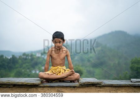 A Young Indian Cute Kid Doing Yoga In The Mountains,wearing A Dhoti