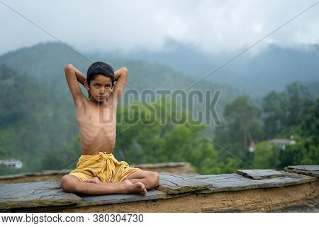 A Young Indian Cute Kid Doing Yoga In The Mountains,wearing A Dhoti