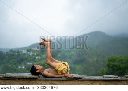 A Young Indian Cute Kid Doing Yoga In The Mountains,wearing A Dhoti