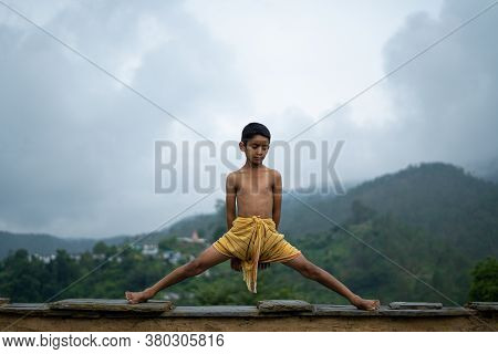 A Young Indian Cute Kid Doing Yoga In The Mountains,wearing A Dhoti