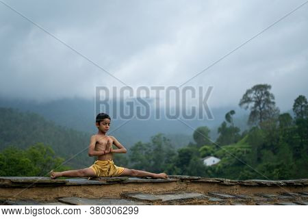 A Young Indian Cute Kid Doing Yoga In The Mountains,wearing A Dhoti