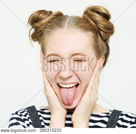 funny girl showing her tongue while posing against studio background