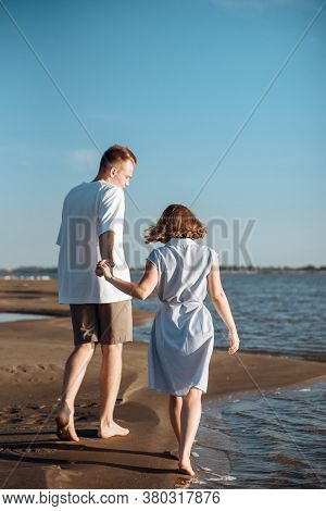 Couple In Love On The Beach.young Man And Woman Walking On Seashore And Laughing.