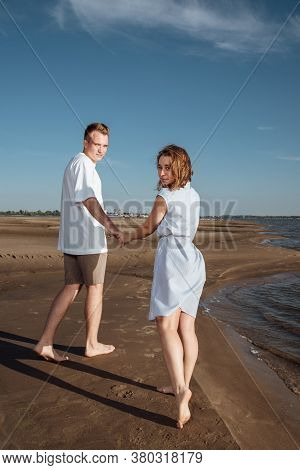 Couple In Love On The Beach.young Man And Woman Walking On Seashore And Laughing.