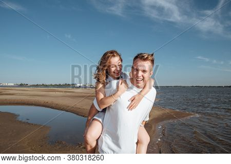 Couple In Love On The Beach.portrait Of A Couple In Love On The Beach. A Young Girl Hugs A Guy.