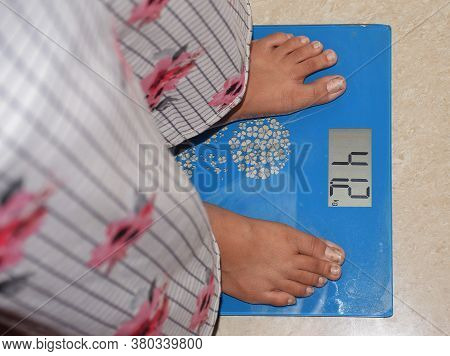 A Girl Measuring Her Weight On A Digital Weighing Machine Or Equipment