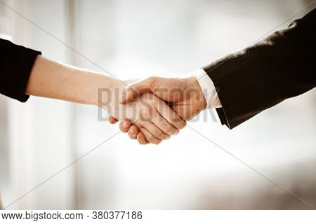 Successful business concept. Young businesswoman and businessman shake hands closeup after signing partnership cooperation contract in office. Two managers man and woman teamwork indoors