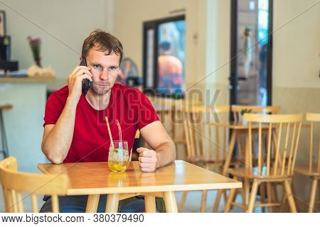 Serious Man Belligerent Put Hand Fist On Table In Front , Answer Phone In Red Shirt In Cafe, Drink T