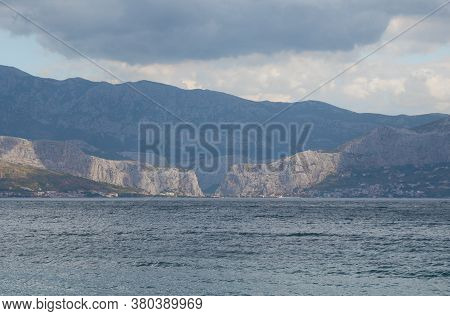 View Of The Town Of Omis In Croatia, Seen From The Island Of Brac From Very Far Away. Two Mountains 