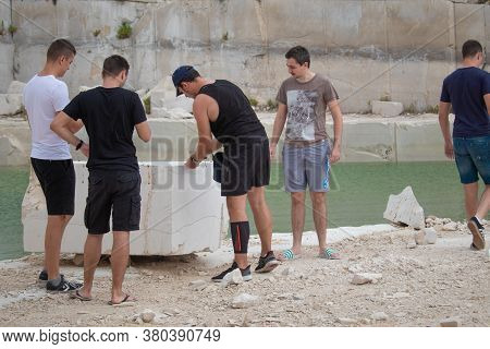 Selca, Croatia August 2020 Group Of Men Inspecting A Large Marble Stone Inside An Abandone Stone Qua