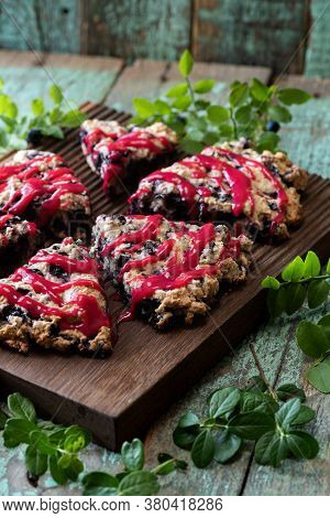 Blueberry Scones With Raspberry Jam Topping On Oak Cutboard With Blueberry Leaves On Old Painted Woo