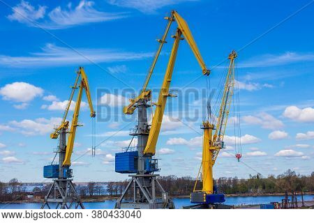 Marine Loading Cranes Of Yellow Color On A Background Of Blue Sky With Clouds. Cargo Transportation.