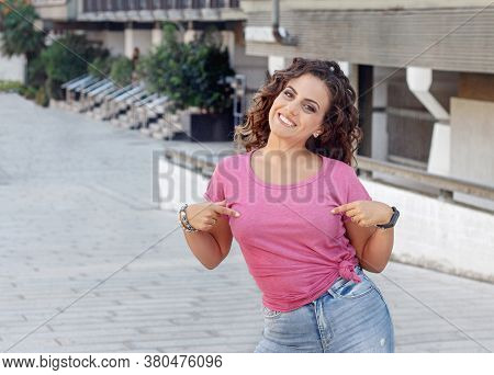 Young Women Wearing T-shirt And Jeans Stays On The Street And Shows In The  Center Of T-shirt