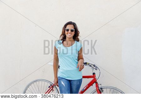 Young Women With Bycicle Stays Near A Wall And Smile