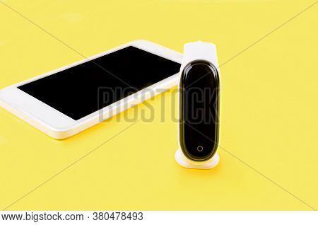 Fitness Tracker With White Braslet And Smartphone On The Yellow Background.  Concept Mobile Modern H