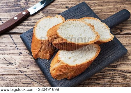 Fresh White Bread Baguette Cut Slays On A Wooden Cutting Board.