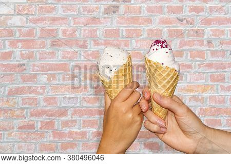 Mother And Daughter Hands Holds Ice Cream Corn With Milk Ice Cream Assing Old Red Brick Wall. Two Ha