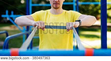 Man stretching with elastic rubber during street workout
