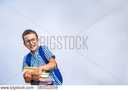 Back To School. Funny Little Boy With Glasses, Laughing Merrily On A Light Gray Background. A Child 