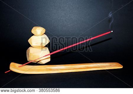 Smoking Incense Stick On Wooden Stand And Wooden Tumi Ishi On Black Background
