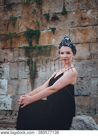 Beautiful Middle-aged Woman In Long Black Dress Sitting On The Stone Near Of Hidirlik Tower, Histori