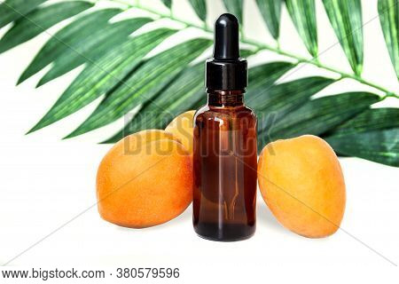 Bottle Of Peach Oil, Decorated With Peaches On Wooden Table And Dark Borwn Background. The Concept O
