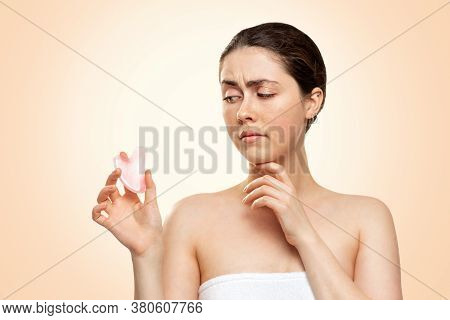Gua Sha Massage. Portrait Of A Young Woman In A Bath Towel Holds A Quartz Guasha Stone In Her Hand, 