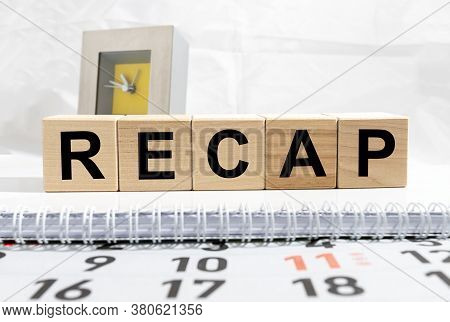 Recap Word From Wooden Blocks On Calendar And Spiral Notebook, Alarm Clock Blurred On Background